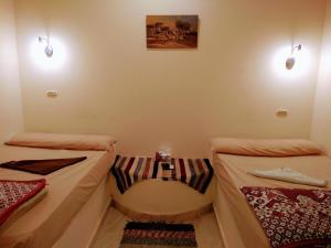 Qasr Al FarafirahにあるRahala Safari Hotelのベッド2台と壁に照明2つが備わる客室です。