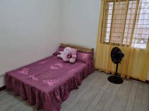 a teddy bear sitting on a purple bed in a room at Simply Ur Home in Lucena in Lucena