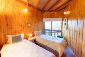 two beds in a room with wooden walls at Kinoie Mornington - OCEANVIEW in Mount Martha