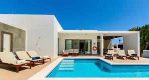 a swimming pool with lounge chairs and a house at Jacks Place Villa PlayaBlanca Pool Spa in Playa Blanca