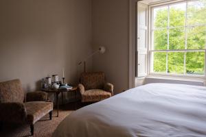 a bedroom with a bed and two chairs and a table at Boath House Hotel in Nairn