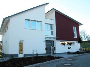 une maison blanche avec un rouge et un blanc dans l'établissement Ferienwohnung am Bienenfeld, à Ettenheim