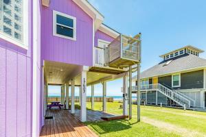 uma casa cor-de-rosa com um deque com o oceano ao fundo em Salty Sandpiper em Galveston