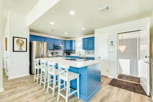 uma cozinha com armários azuis e uma grande ilha com bancos em Salty Sandpiper em Galveston