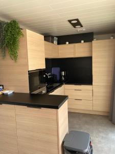 une cuisine avec des placards en bois et un comptoir noir dans l'établissement Chalet, à Labouheyre