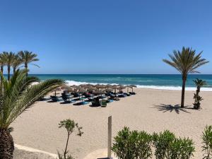 Una playa con sillas y sombrillas y el océano. en Lovely New Luxery Beach Apartment in Mojacar Playa next to the best beach, en Mojácar