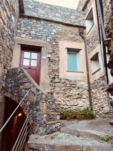 a stone house with a red door and stairs at Spacious 2 bedroom condo in Colletta