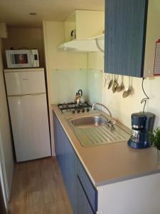 a small kitchen with a sink and a refrigerator at Mobile home Ameglia - Including airco - Camping River- 328 in Ameglia