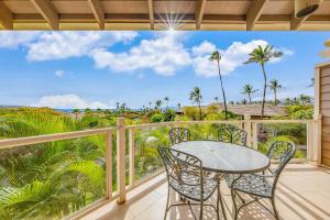 a balcony with a table and chairs and palm trees at Wailea Grand Champions 58 in Wailea