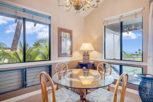 a dining room with a glass table and chairs and windows at Wailea Grand Champions 58 in Wailea