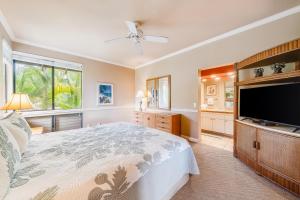 a bedroom with a large bed and a flat screen tv at Wailea Grand Champions 58 in Wailea