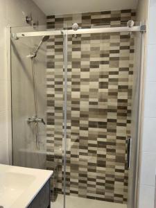 La salle de bains est pourvue d'une douche avec une porte en verre. dans l'établissement APARTAMENTO EL LLANO, à Lucena