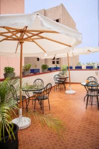 een patio met tafels, stoelen en parasols bij RIAD DOUIRTNA in Marrakesh