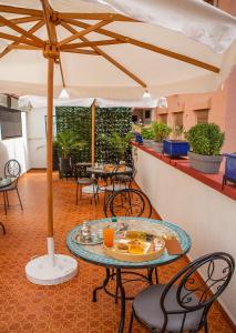 d'une terrasse avec des tables, des chaises et un parasol. dans l'établissement RIAD DOUIRTNA, à Marrakech