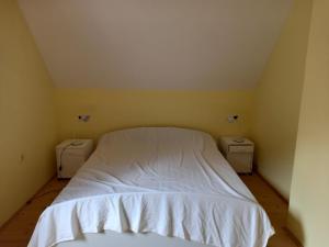 a bedroom with a white bed and two night stands at Adventure Land in Jablanica