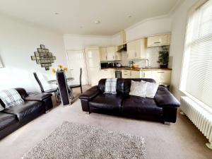 a living room with a leather couch and a kitchen at Vitamin Sea Beachfront Apartment Ramsgate - Sleeps 4 in Ramsgate