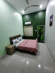 a bedroom with a bed and a green wall at HOMESTAY DR. Z (MUSLIM HOMESTAY) in Klang