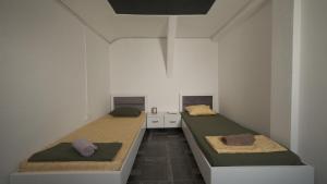 two beds in a room with white walls at Hostel Dera in Pristina