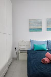 - une chambre dotée d'un lit avec des oreillers bleus et roses dans l'établissement Cosy, Modern 1 Bedroom Apartment (Qawra), à San Pawl il-Baħar