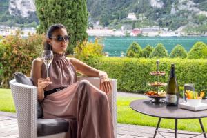 a woman sitting in a chair with a glass of wine at Lido Palace - The Leading Hotels of the World in Riva del Garda