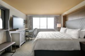 um quarto de hotel com uma cama, uma secretária e uma televisão em Holiday Inn Montreal Longueuil, an IHG Hotel em Longueuil
