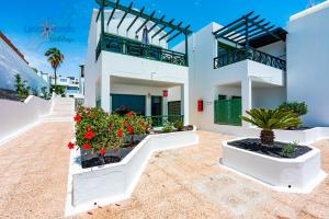 a white building with flowers and plants in front of it at Vivienda Vacacional Casa Evy in Puerto del Carmen