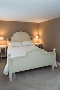 a white bed in a room with two lamps at The Ynys Lodge in Pwllheli
