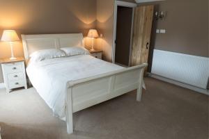 a bedroom with a large white bed and two lamps at The Ynys Lodge in Pwllheli