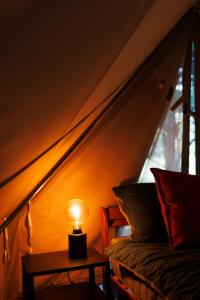 a lamp on a table next to a bed and a window at Glamping - Projekt Alpaka in Garbatka-Letnisko