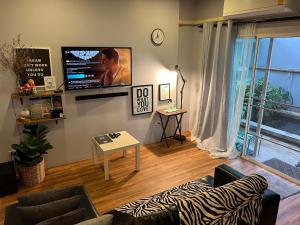 a living room with a couch and a flat screen tv at Mini-ME Home, A Cozy Entire House in Old City in Chiang Mai