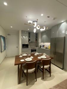 a kitchen with a wooden table with chairs and a refrigerator at Two Bedroom Apartment Address Residence - Fujairah in Fujairah