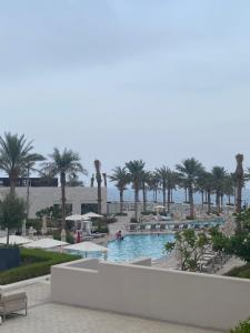 a swimming pool with palm trees in a resort at Two Bedroom Apartment Address Residence - Fujairah in Fujairah