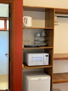 La cocina está equipada con microondas y nevera. en Barra do Bié Suítes, en Cunha