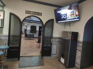 Habitación con puerta y TV en la pared en Hostal Restaurante Bar Cafeteria La Melchora, en Posadas