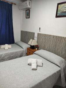1 dormitorio con 2 camas y mesa con lámpara en Hostal Restaurante Bar Cafeteria La Melchora, en Posadas