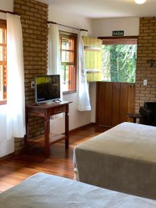 um quarto com 2 camas e uma secretária com uma televisão em Barra do Bié Suítes em Cunha