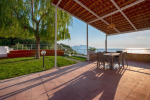a patio with a table and chairs and a view of the water at Villa Il Canto delle Sirene in Marciano