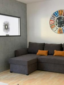 a couch in a living room with a clock on the wall at Appartement by Luis in Burgheim