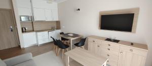 a kitchen with a table and a television on the wall at Apartamenty ELIASZ in Ustronie Morskie +26 photos