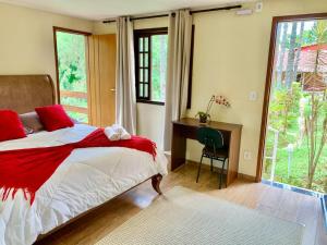 a bedroom with a bed and a desk and windows at Recanto de Moriá in Penedo