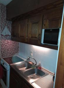 eine Küche mit einer Spüle und einer Mikrowelle in der Unterkunft Appartement chalet en plein centre des Saisies in Hauteluce