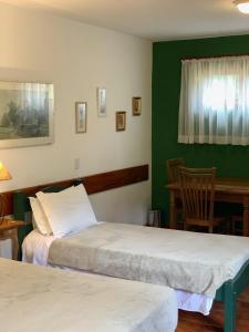 Habitación con 2 camas, mesa y silla en Barra do Bié Suítes en Cunha