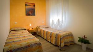 a bedroom with two beds and a window and a lamp at Hotel Venezia in Caorle