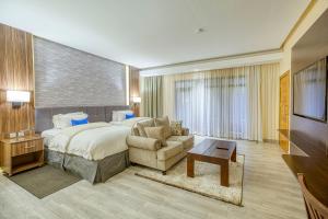 een slaapkamer met een bed, een stoel en een bank bij Virunga Inn Resort & Spa in Kinigi