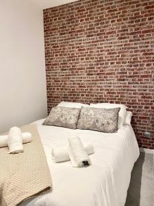 a large white bed with a brick wall at L'Atelier in Beauvais