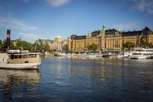 a boat in a river in front of buildings at Crystal Plaza Hotel in Stockholm
