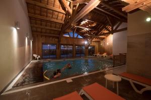 a pool in a building with two people swimming at Hôtel Soleil des Neiges in Le Sauze