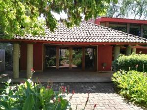 a red house with a patio in front of it at Nice home with gardens and trees, 3 full bedrooms, living and kitchen in León +14 photos