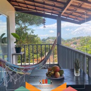 a table with a plate of fruit on a balcony with a hammock at Vila Pepouze Hostel in Morro de São Paulo