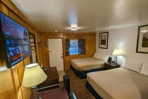 um quarto de hotel com duas camas e uma televisão de ecrã plano em Teton Court Motel em Pinedale